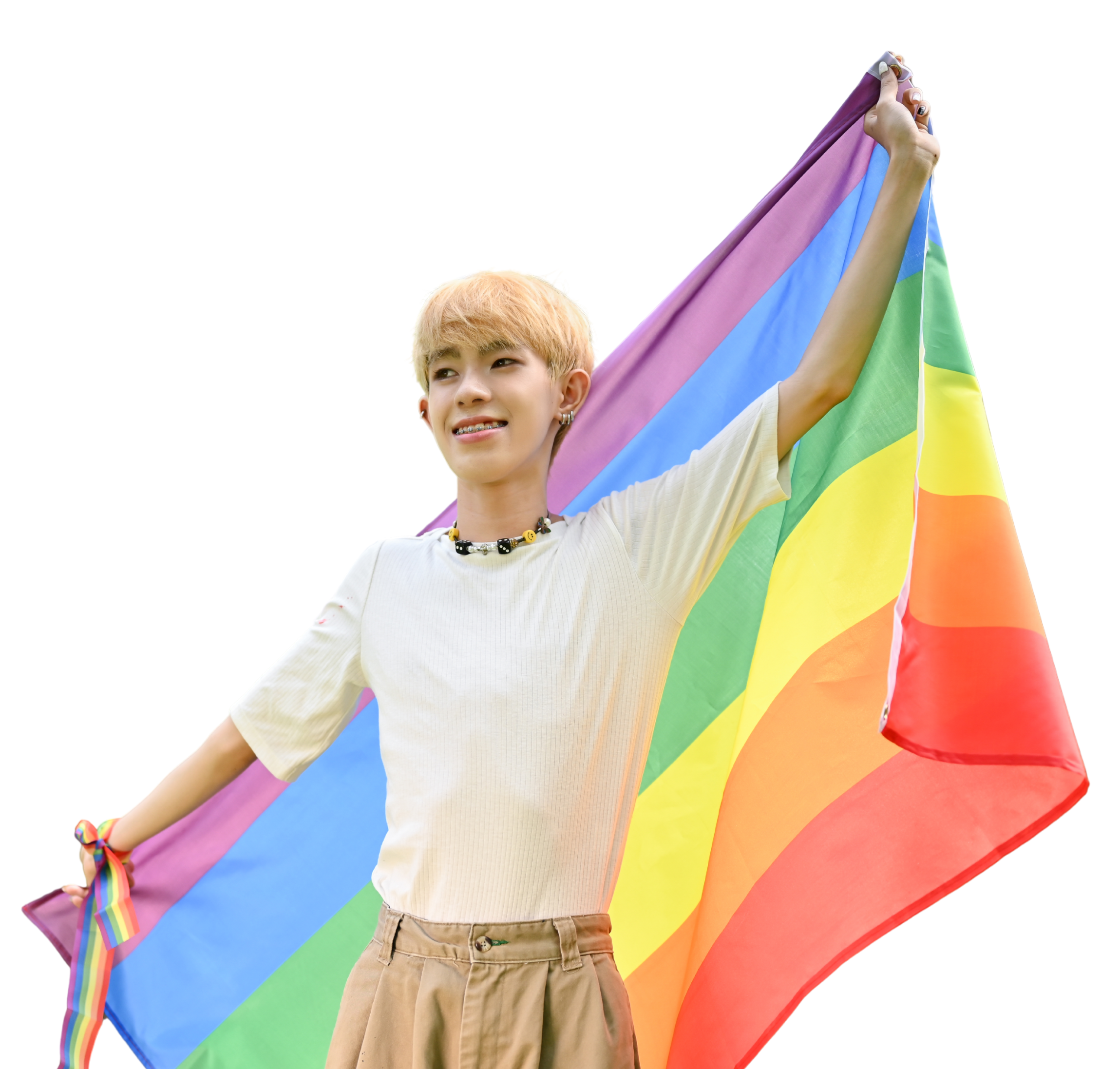A young person holding a rainbow flag behind them with both arms outstretched.